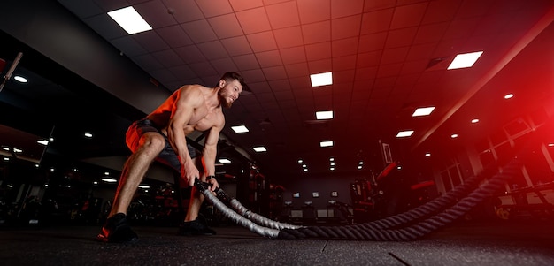 Sterke shirtloze man die hard traint in de sportschool. Knappe bodybuilder die hard werkt.