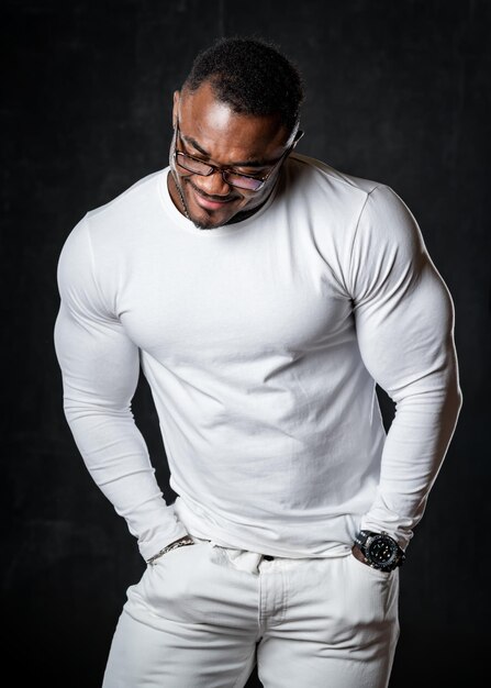 Sterke sportieve Afro-Amerikaan met grote spieren poseert voor de camera in totaal witte look. Sportief gezond lichaam. Vooraanzicht.