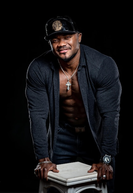 Sterke sportieve Afro-Amerikaan met grote spieren poseert voor de camera met losgeknoopt shirt. Sportief gezond lichaam. Vooraanzicht.