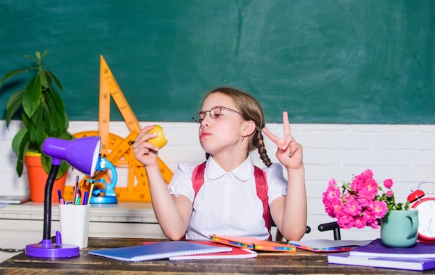 Sterke tanden klein meisje klaar om appel te eten Slim kindconcept digitaal tijdperk met moderne technologie klein geniaal kind in de klas Lunchtijd gezond eten is goed terug naar school Einstein