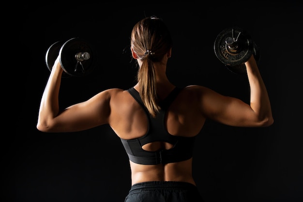 Sterke vrouw met halters, een slank meisje houdt een haltertraining voor een sexy lichaamsfitness, sexy vrouw met