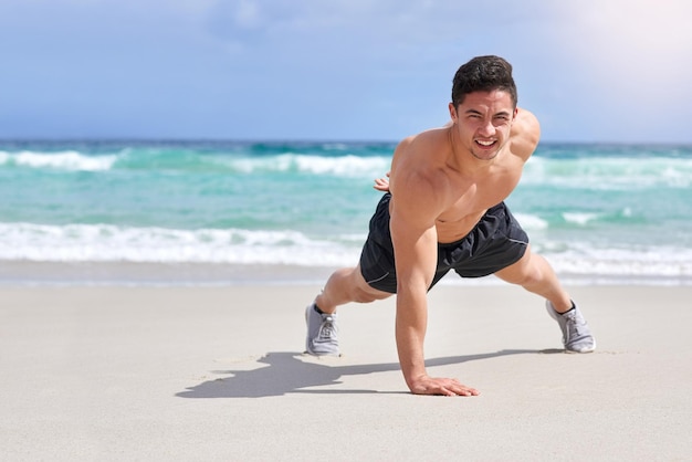 Sterker worden met elke rep Portret van een knappe jonge man die met één hand push-ups doet op het strand