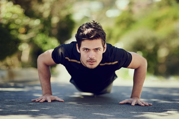 Sterker worden Volledig portret van een knappe jonge man die buiten push-ups doet