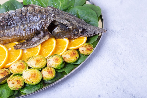 Sterlet baked (Sturgeon) with spinach, oranges and Brussels sprouts. Russian cuisine. Close-up.