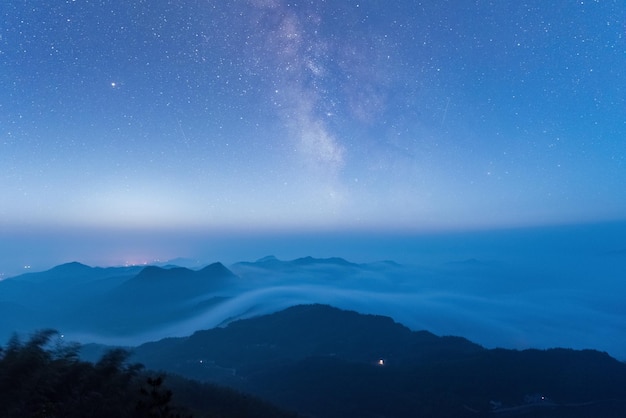 Sterrenhemel op de bergtop en wolkenmist in de vroege uren van de ochtend