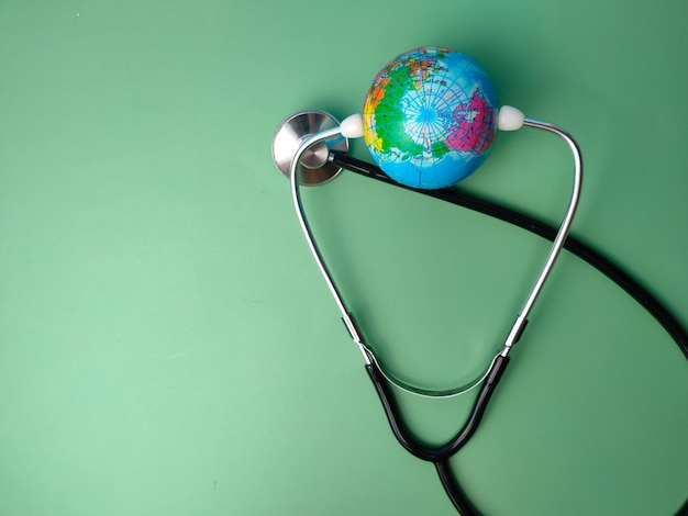 Stethoscoop en earth globe op een groene achtergrond Gezondheidszorg en medische concept