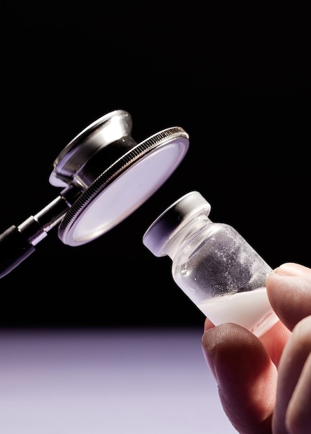 Stethoscoop en glazen flaconvaccin in de hand van de arts