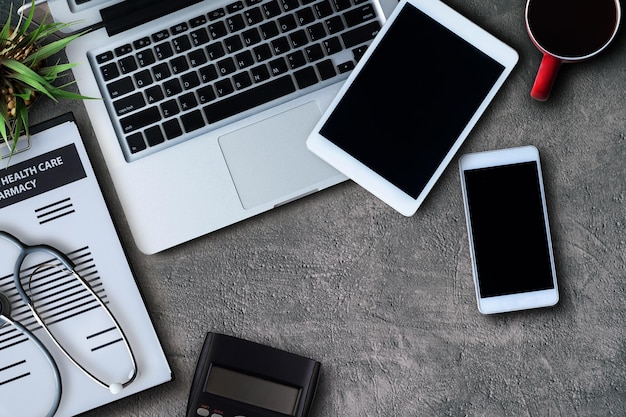 Stethoscoop hart pen laptop smartphone muis en kopje koffie op het bureau Bovenaanzicht met kopieerruimte