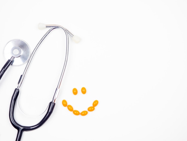 stethoscoop met pillen in de vorm van een glimlach op een witte achtergrond