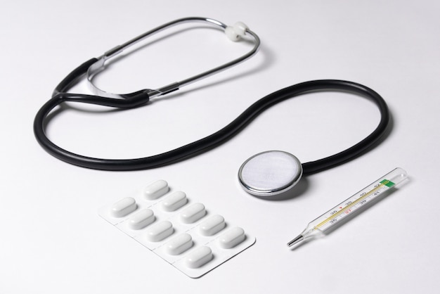 Stethoscoop, thermometer, pillen, op een witte achtergrond