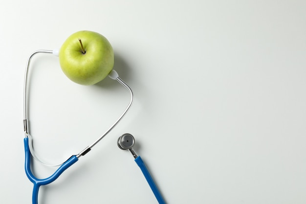 Stethoscope and apple on white background, space for text