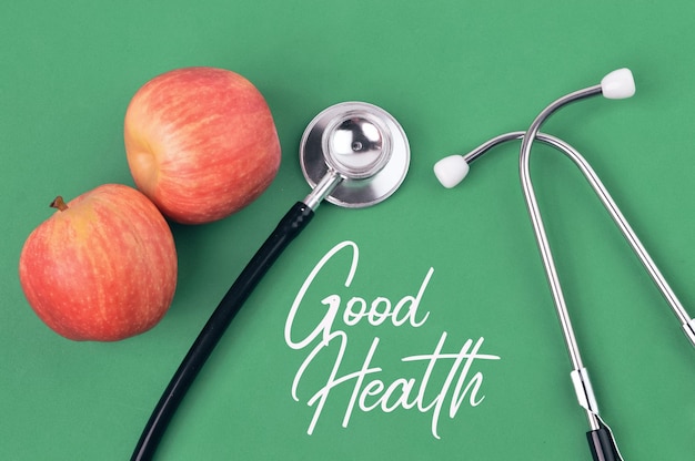 Photo stethoscope and apples over green background written with text good health