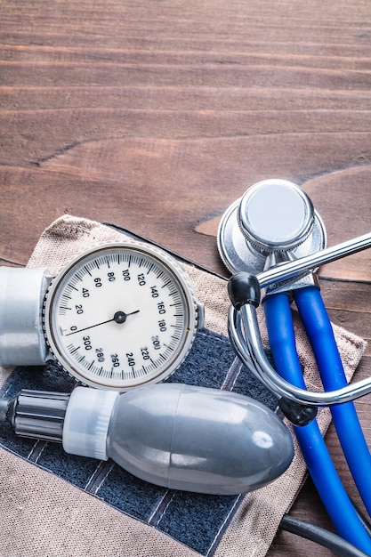 Stethoscope and blood pressure monitor on vintage wooden board with copyspace medical comcept