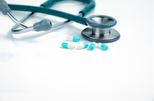 Stethoscope and blue-white capsule pills on doctor table or nurse desk. Health checkup.