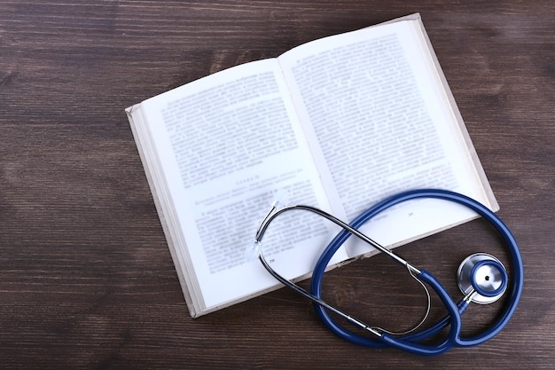 Photo stethoscope on book on wooden table top view