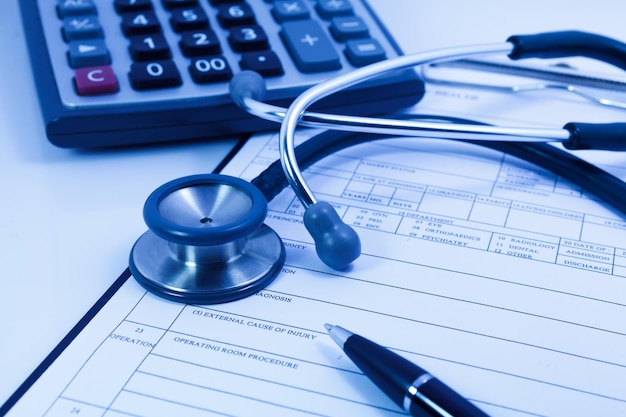 Stethoscope calculator and pen on blank Patient information