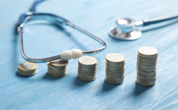 Stethoscope and coins on the blue background.