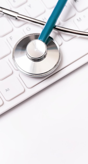 Stethoscope on computer keyboard on white background Physician write medical case long term care treatment concept close up macro copy space