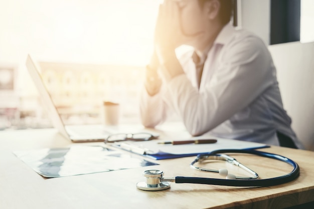 Stethoscope and doctor sitting with laptop  stress headache about work in hospital