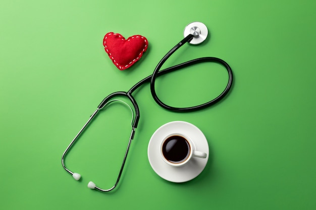 Stethoscope in doctors desk with cup coffee and heart