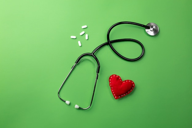 Stethoscope in doctors desk with heart and pills