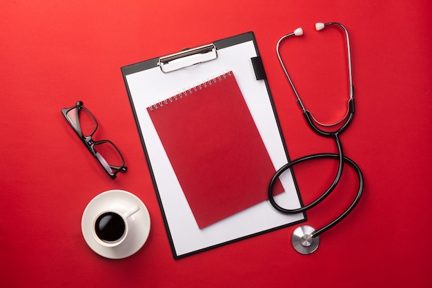 Stethoscope in doctors desk with tablet and coffee cup. Top view with place for your text.