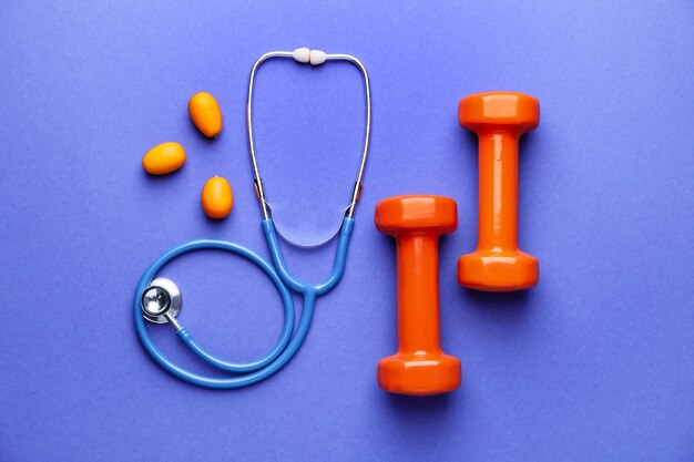 Stethoscope, fruit and dumbbells on color