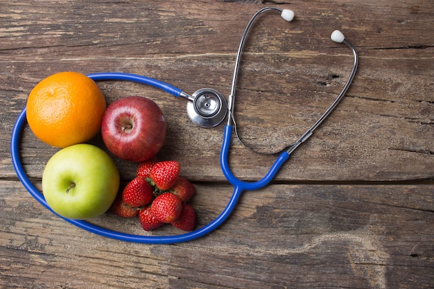 Stethoscope and fruits on wood