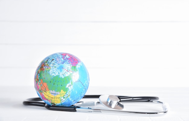 Stethoscope and globe on white wooden background. Healthcare and medical concept.