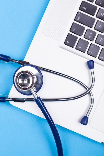 Stethoscope over a gray laptop in close up image on blue background