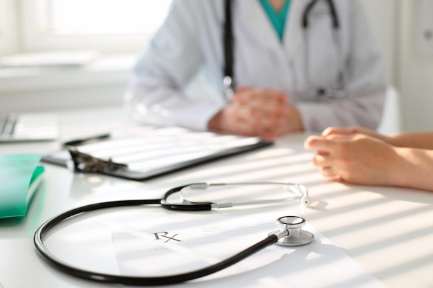 Stethoscope next to hand of doctor  reassuring her female patient. Medical ethics and trust concept