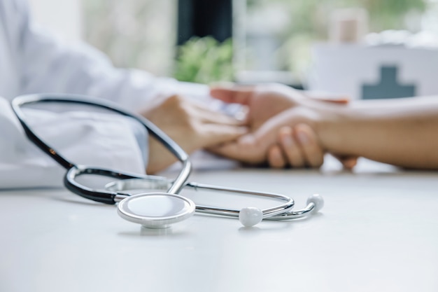 Stethoscope and hand of doctor reassuring male patient