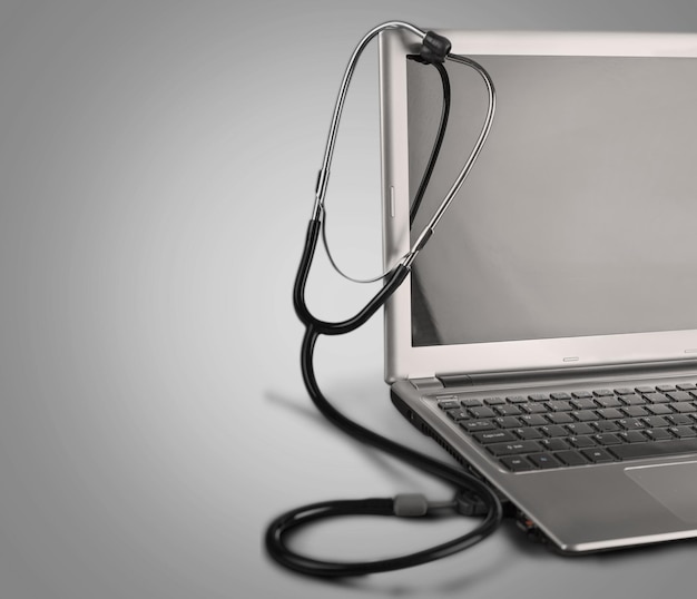 Stethoscope hang on laptop  on wooden background