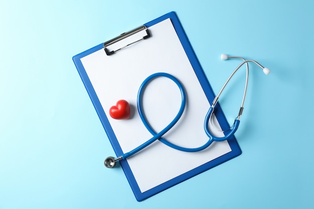 Stethoscope and heart on blue background, space for text