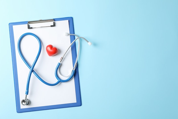 Stethoscope and heart on blue background, space for text