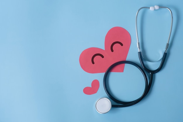 Stethoscope and heart on blue background top view