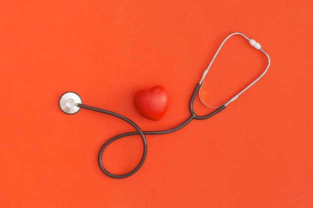 Stethoscope and heart on red background top view flat lay\
medicine concept