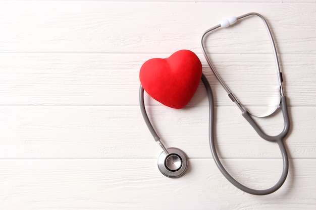 Стетоскоп и сердце на деревянном фоне цвета. Здоровье, медицина. Фото высокого качества