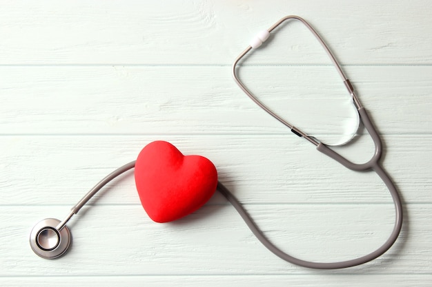 木製の色の背景の健康医学の聴診器と心臓