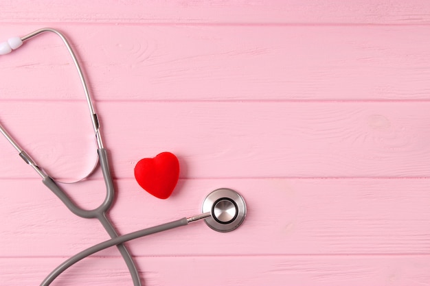 Стетоскоп и сердце на деревянном цветном фоне медицины здоровья