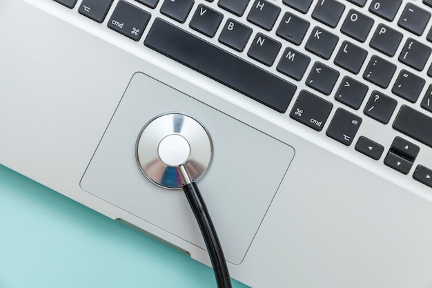 Stethoscope keyboard laptop computer isolated on blue background.