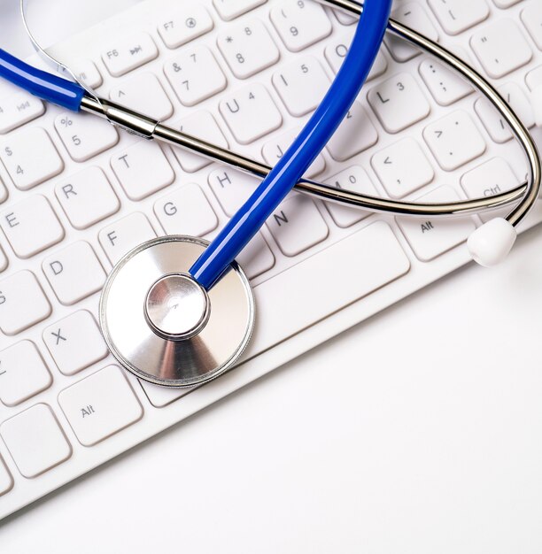 Stethoscope on keyboard on white table background.