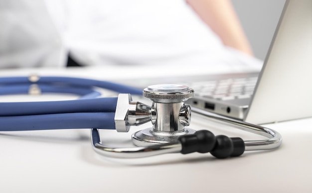 Stethoscope and laptop at doctor table Devices for online treatment of patients and physical consultation Health care and medicine concept