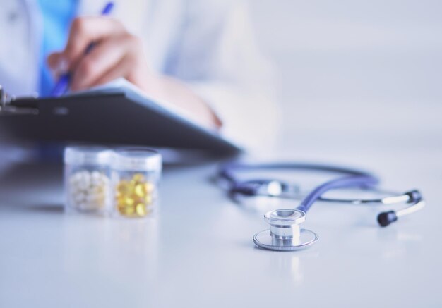 Stethoscope lying on glass desk with laptop computer at busy physician background Medicine or pharmacy concept Medical tools at doctor working table