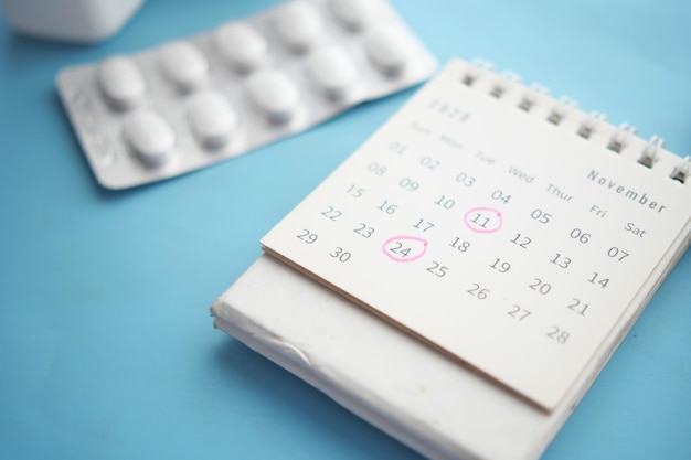 Stethoscope medical pill container and calendar on color background