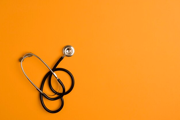 Stethoscope medicine accessory, orange background with copy space.