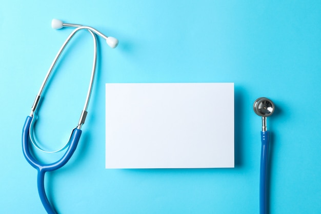 Stethoscope and notepad on a blue background, space for text