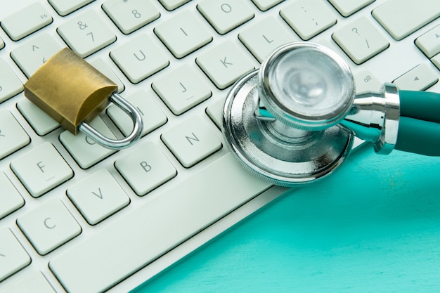 stethoscope and padlock on a keyboard on blue background