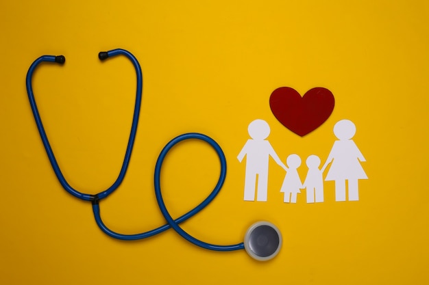 Stetoscopio e catena di carta famiglia, cuore rosso su giallo, concetto di assicurazione sanitaria