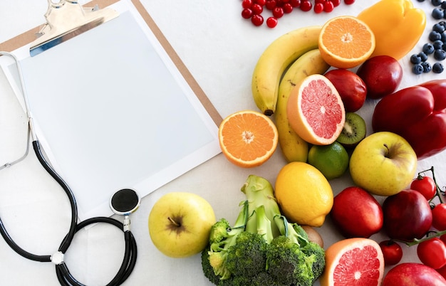 Stethoscope paper on tablet with empty space fruits berries and vegetables